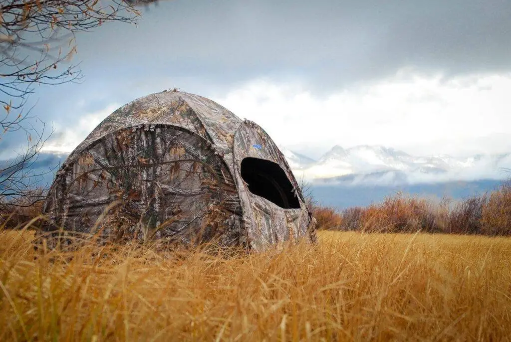two man pop up hunting blind in wilderness with mountain background